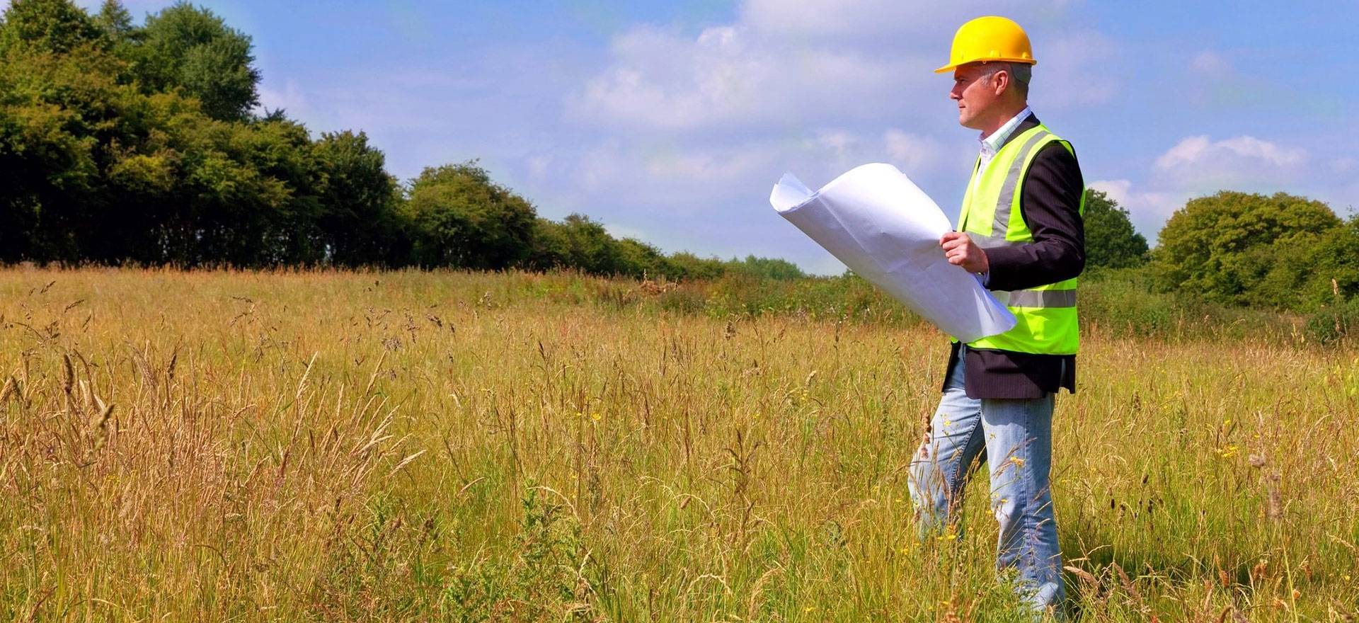 Architect wearing site safety gear and holding a set of plans