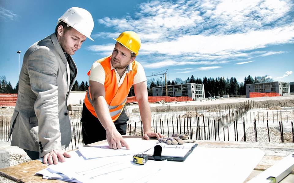 Two engineer reviewing blueprints for construction at construction site.